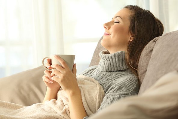 Lady holding a cup under a blanket