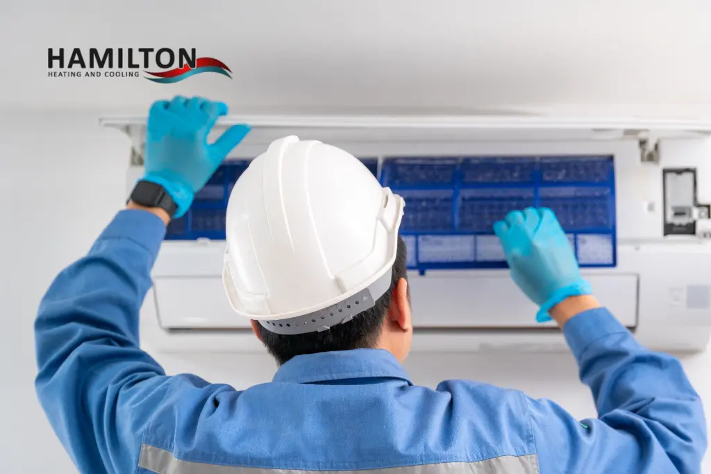 Technician performing an AC Tune-Up in Hamilton to prepare an air conditioner for humid summer weather.