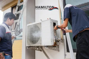 Emergency AC repair in Hamilton technician fixing air conditioner unit