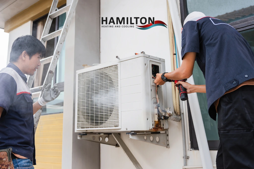 Emergency AC repair in Hamilton technician fixing air conditioner unit